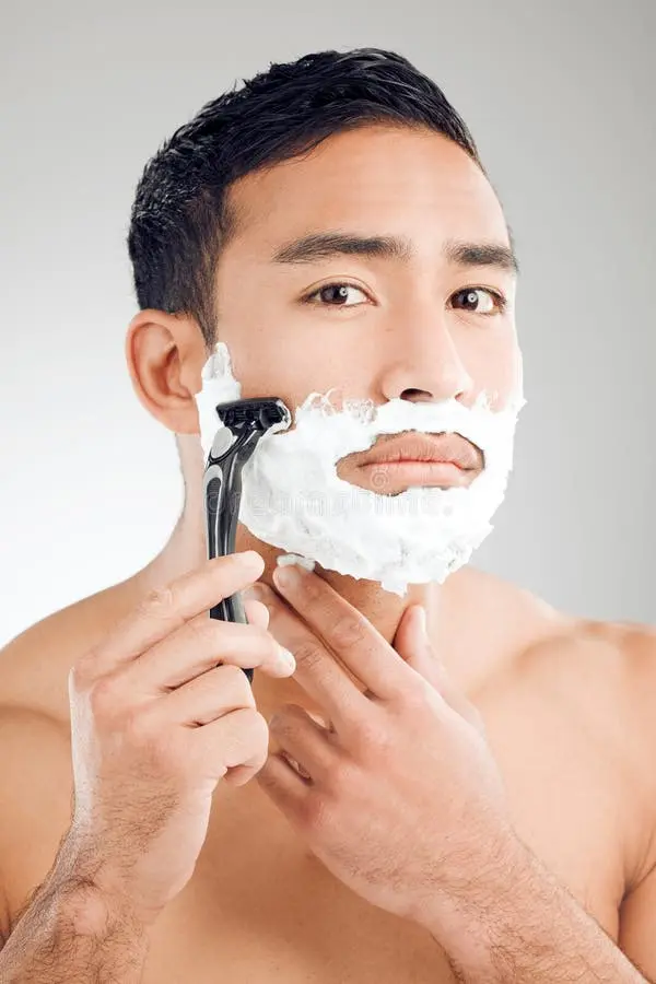 آرایشگر در حال ریش تراشی با تیغ برای پوست صاف و بدون تحریک