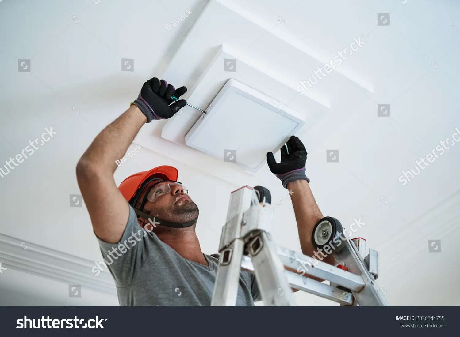 کارگر الکتریکی در حال نصب چراغ LED در سقف